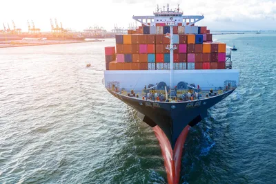 Poynting A-WHUNTER-001-V3-102 Marine-5G/LTE-Antenne für Containerschiffe mit Hafen im Hintergrund bei klarem Wetter.