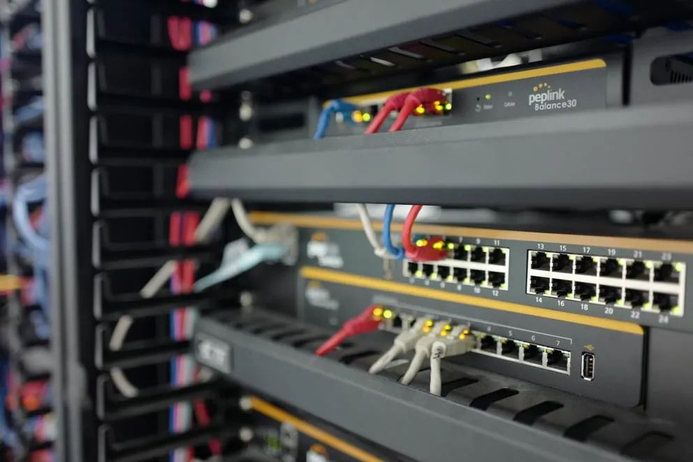 Licenza FIPS per Balance 310, dispositivo Peplink Balance 30 in rack con cavi Ethernet e fibra ottica illuminati.