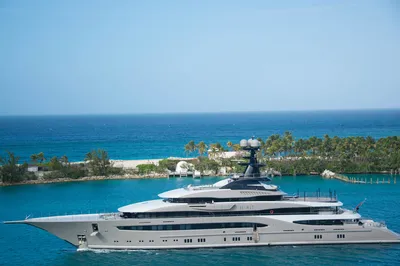 Poynting A-WHUNTER-001-V3-102 5G/LTE-Marineantenne auf schwarzem Mast einer Luxusyacht vor tropischer Küste.