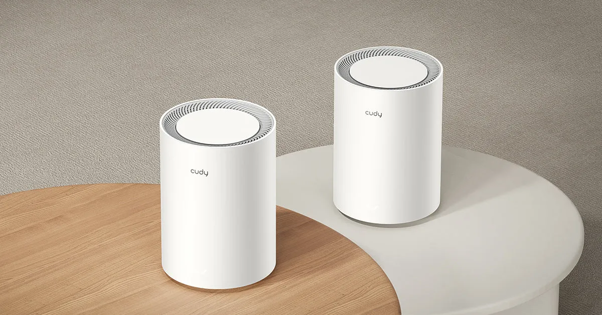 Cudy M3000 sistema Wi-Fi Mesh dos nodos cilíndricos blancos con rejilla en mesa de oficina. Cudy M3000 sistema Wi-Fi Mesh dos nodos cilíndricos blancos con rejilla en mesa de oficina.
