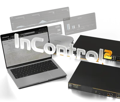 Peplink Balance 580X с двумя чёрными маршрутизаторами и ноутбуком на фоне панели InControl2 с графиками и данными.