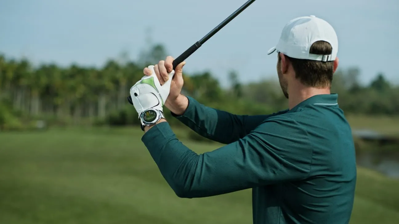 HUAWEI WATCH Ultimate 2 March-B29 in blue and white fluoroelast worn on wrist during golf swing with club raised.