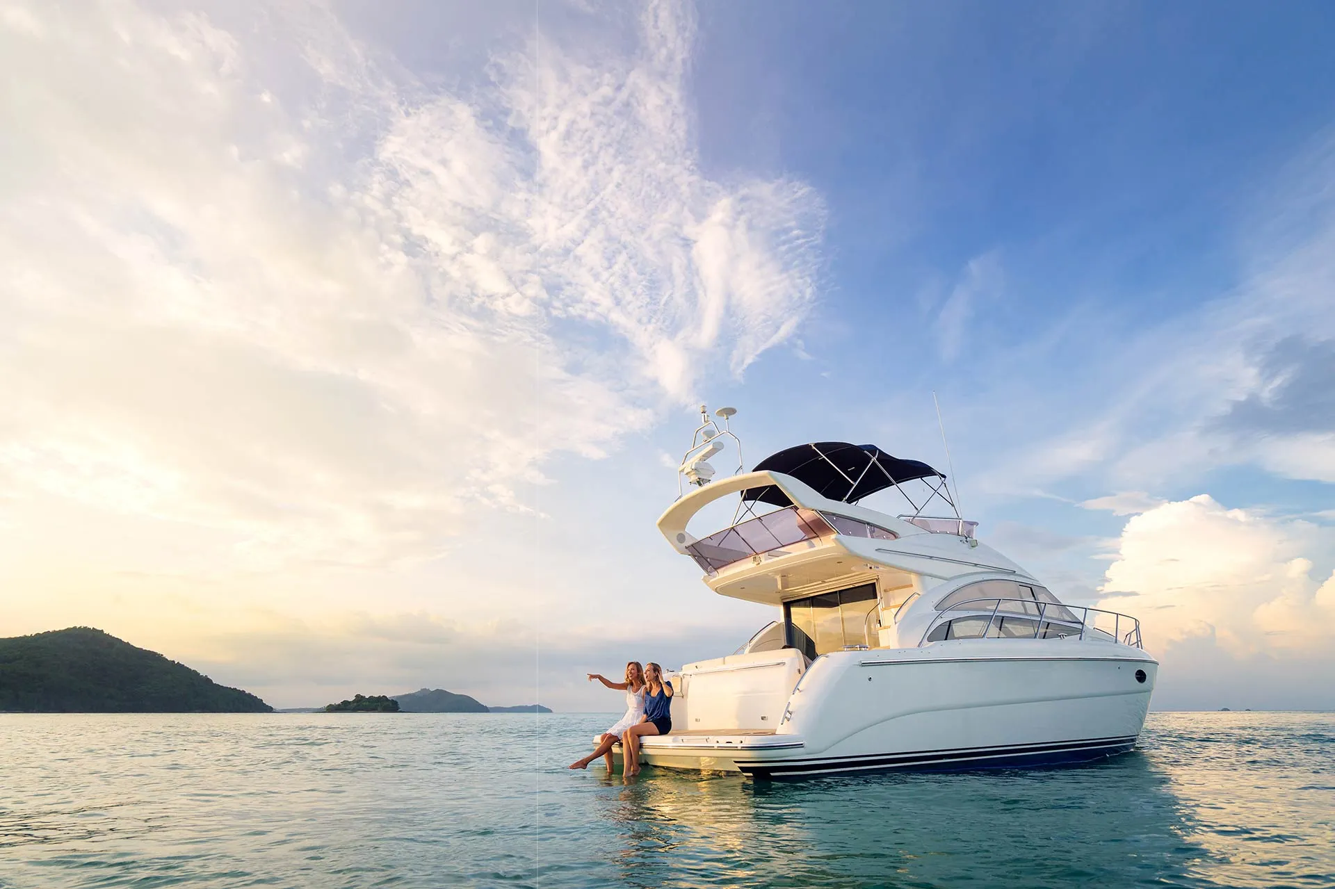 Antenne Poynting A-MIMO-0004-V2-17-W blanche 5G/LTE pour yacht avec deux femmes sur la plateforme arrière admirant l’horizon. Antenne Poynting A-MIMO-0004-V2-17-W blanche 5G/LTE pour yacht avec deux femmes sur la plateforme arrière admirant l’horizon.