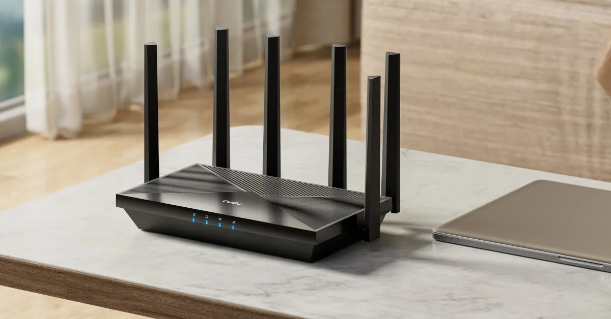 Conmutador inalámbrico Cudy con 6 antenas sobre mesa de mármol junto a portátil para conexión de red doméstica. Conmutador inalámbrico Cudy con 6 antenas sobre mesa de mármol junto a portátil para conexión de red doméstica.