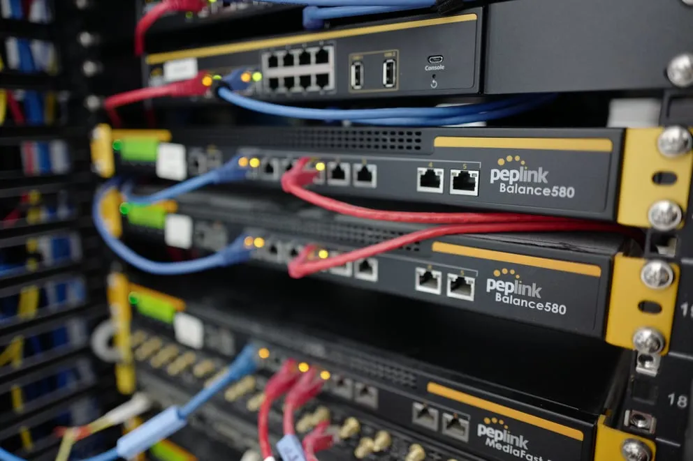 Licenza FIPS per Balance 310, dispositivi Peplink Balance 580 neri montati su rack con cavi ethernet rossi e blu e LED di