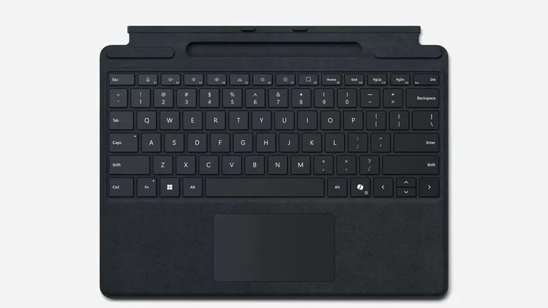 Black Microsoft Surface Pro Type Cover with Spanish layout, full keyboard view showing keys, trackpad, and pen storage slot.