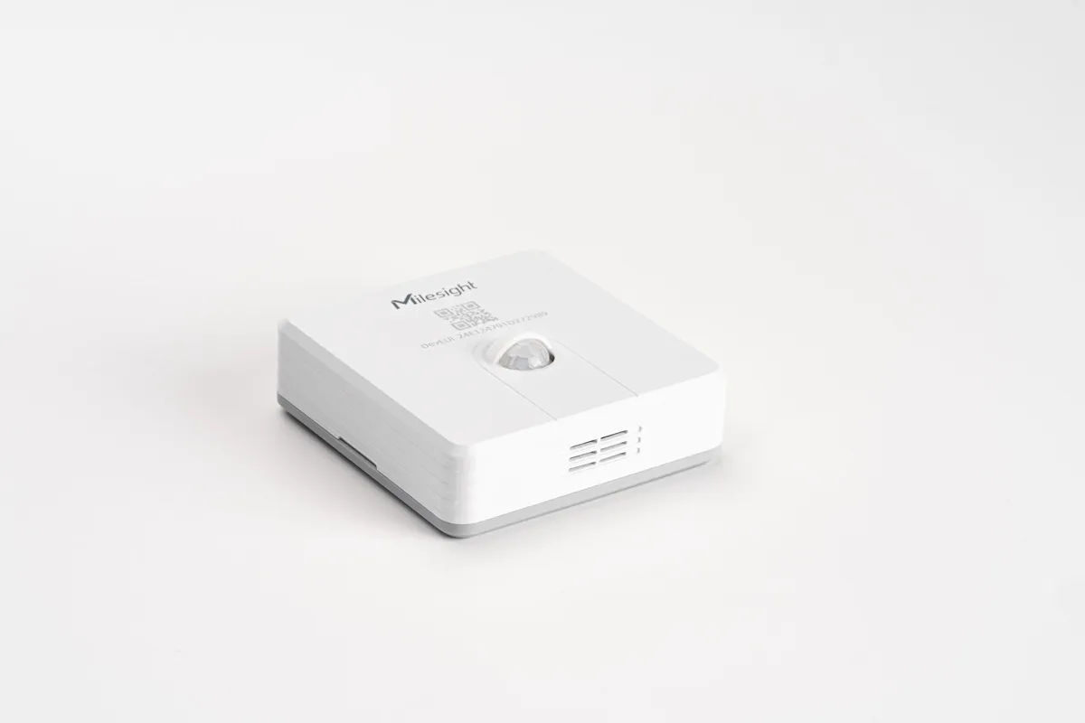 Sensor Milesight WS203-868M de movimiento y temperatura en ángulo alto sobre fondo blanco, con logo, código QR, DevEUI y Sensor Milesight WS203-868M de movimiento y temperatura en ángulo alto sobre fondo blanco, con logo, código QR, DevEUI y
