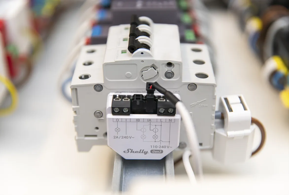 Shelly EM Gen3 energy meter with 50A clamp installed on DIN rail in electrical panel for WiFi power monitoring.