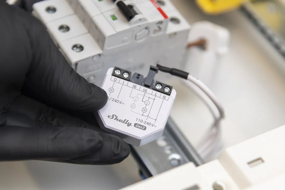 Shelly EM Gen3 under-mount energy meter held in hand with connected 50A terminal and wiring diagram for WLAN smart power