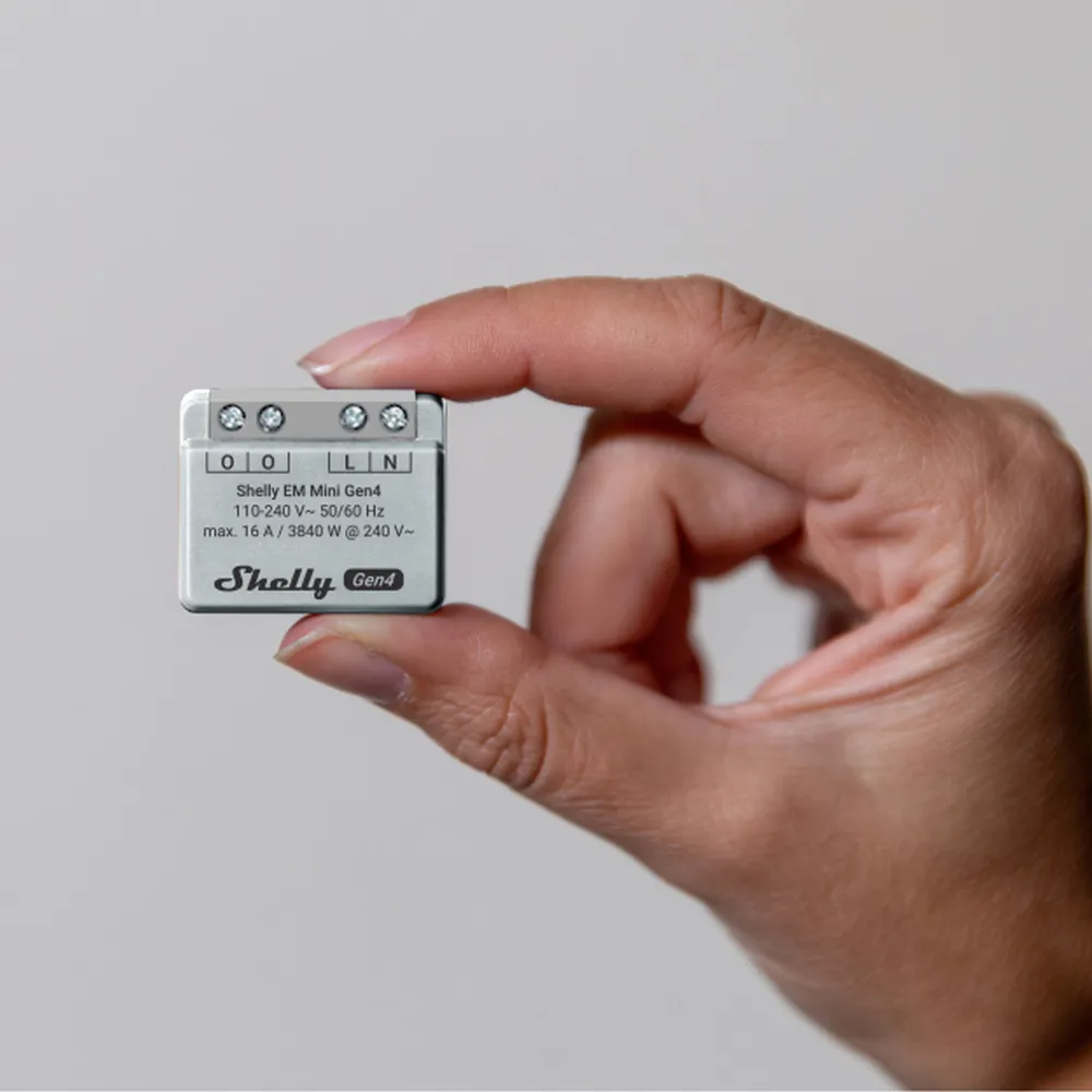 Shelly EM Mini Gen4 smart relay held in hand with four screw terminals labeled O O L N and 110-240V rating against light