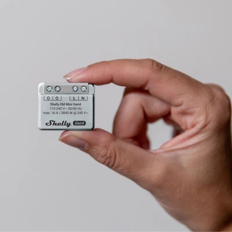 Shelly EM Mini Gen4 smart relay held in hand with four screw terminals labeled O O L N and 110-240V rating against light