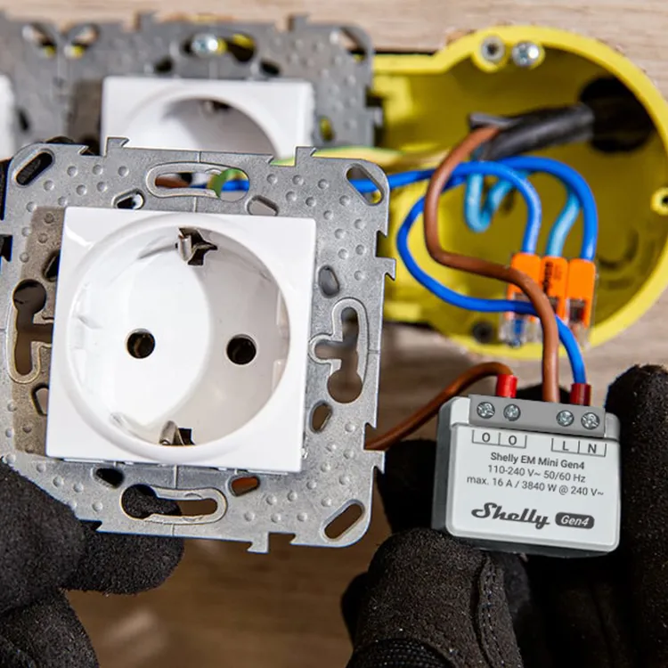 Shelly EM Mini Gen4 relay module wired to a white European socket with blue and brown wires in an electrical installation
