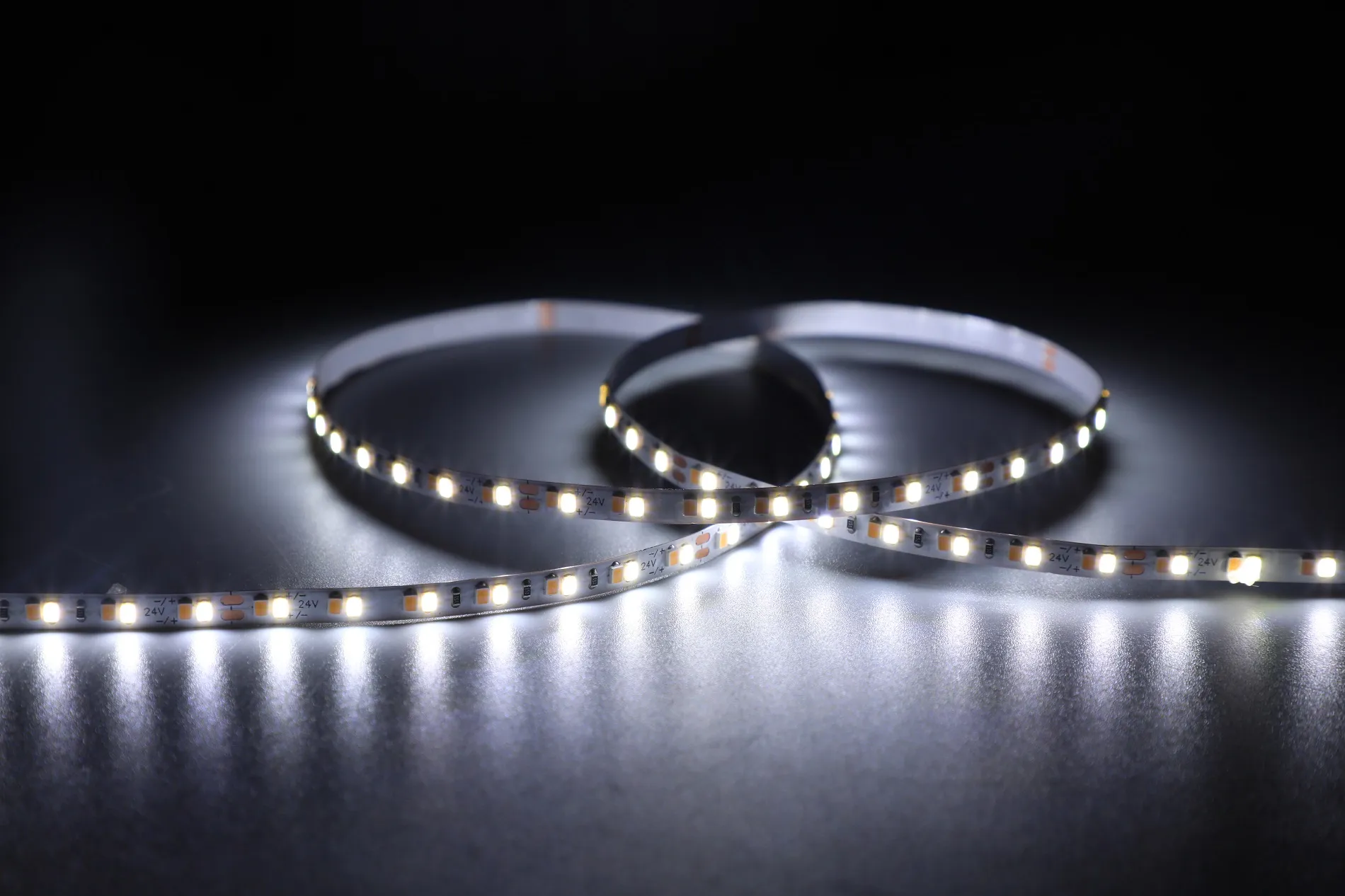 Bande LED flexible Synergy 21 3528 224 DW enroulée éclairée sur surface réfléchissante, 24V CCT DC24V 20W IP20 CRI>80. Bande LED flexible Synergy 21 3528 224 DW enroulée éclairée sur surface réfléchissante, 24V CCT DC24V 20W IP20 CRI>80.