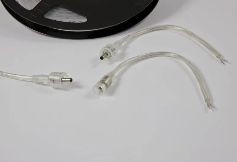Synergy 21 LED Flex Strip 5050 connectors with waterproof seals and pins next to a black reel on a white surface. Synergy 21 LED Flex Strip 5050 connectors with waterproof seals and pins next to a black reel on a white surface.