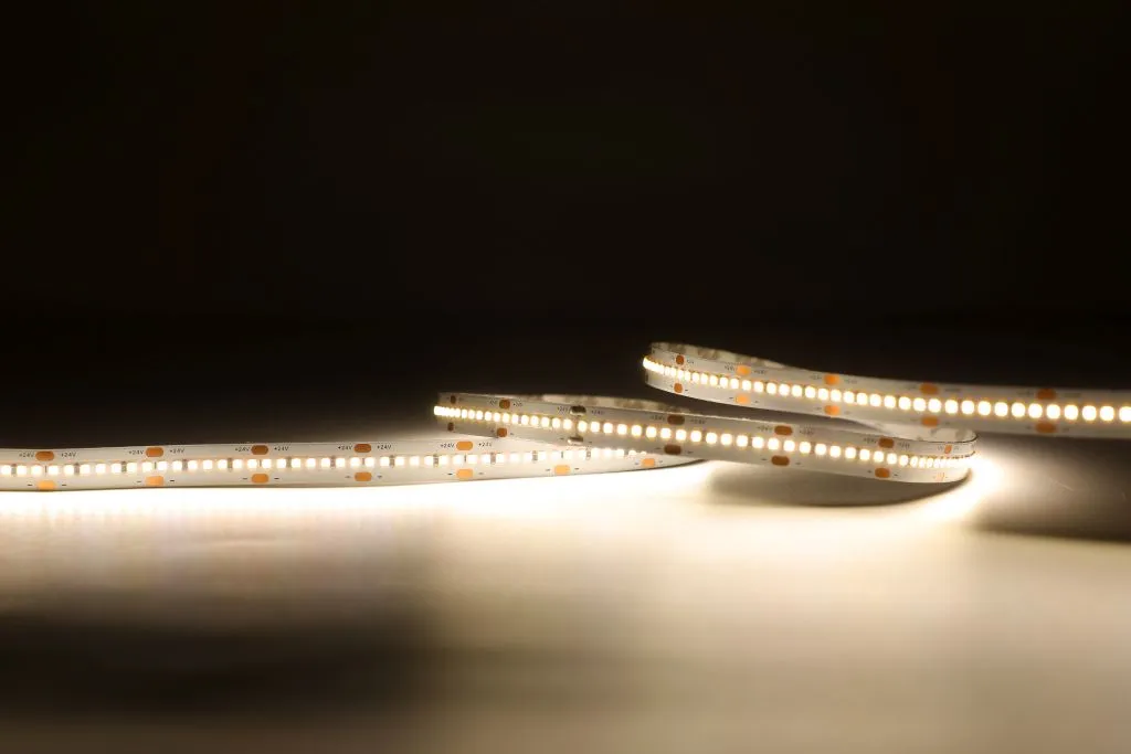 Гибкая светодиодная лента Synergy 21 LED Flex Strip 280 SWW DC24V 96W IP20 свёрнута в рулон на тёмной поверхности с тёплым Гибкая светодиодная лента Synergy 21 LED Flex Strip 280 SWW DC24V 96W IP20 свёрнута в рулон на тёмной поверхности с тёплым