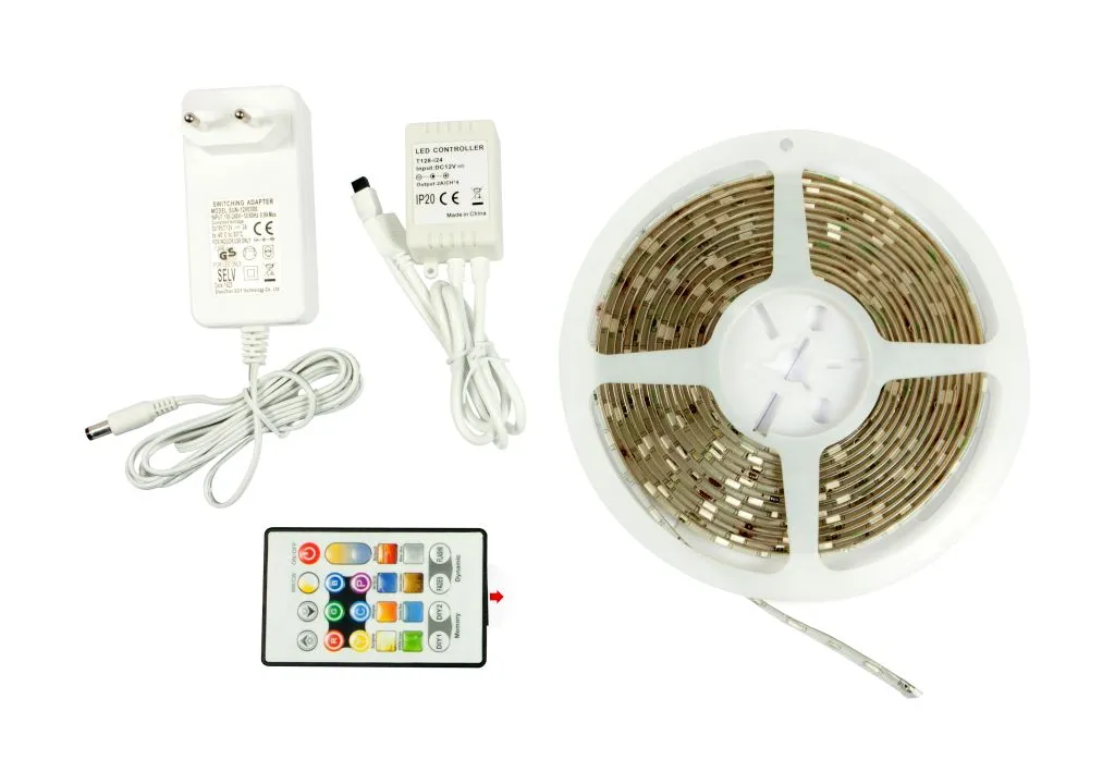 Kit Synergy 21 LED Flex Strip RGB DC12V complet avec adaptateur, télécommande et bande LED déroulée sur fond blanc.
