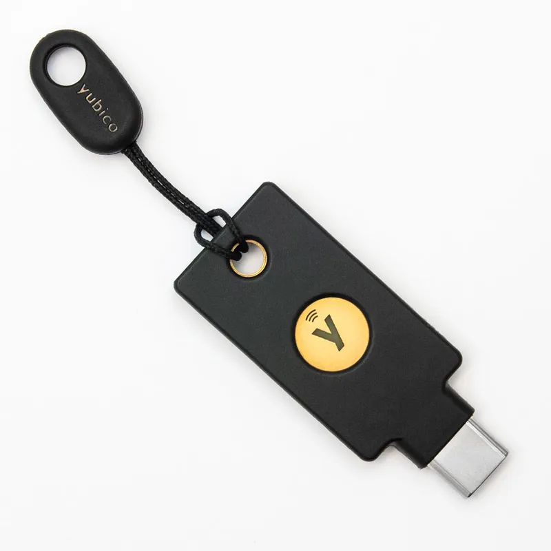 Clé de sécurité Yubico YubiKey USB-C noire avec bouton doré et logo NFC attachée à un cordon ParaPull Keyport noir et doré